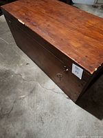 Photo of the rectangular wood trunk showing the top surface with visible scratches and damage including a split on top.