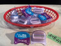 12 Gillette Venus Breeze razor cartridges in individual plastic packaging and loose in a red basket