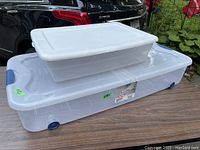 Two Sterilite under bed storage boxes, one large with wheels and one smaller stacked on top