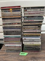 Photo showing two tall stacks of various music CDs from artists including Whitney Houston, Celine Dion, Julio Iglesias, Madonna, Genesis, Barbra Streisand, and others.