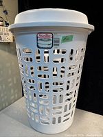 Photo showing the front view of the white plastic Sterilite clothes hamper with lid and vented rectangular pattern.