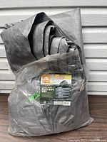 Photo of folded gray tarp with packaging label, showing overall size and folded material.