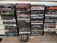 Large lot of DVDs stacked in columns showing various TV series and movie titles including multiple CSI titles, Harry Potter series, and Twilight movies with cases.