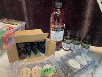 Photo showing large 1000 ml bottle of jojoba clear carrier oil, three smaller amber bottles, cardboard box with eight amber dropper bottles, and two bubble wrapped items.