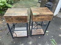 Pair of wood end tables with sliding tops closed, showing rustic wood finish and metal legs with mesh lower shelf.