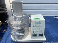 Front view of Proctor-Silex food processor showing clear plastic bowl, feed chute, and attached power cord.