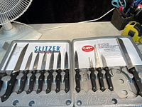 Full view of 17-piece Slitzer knife set in foam case showing all knives with black handles and stainless steel blades