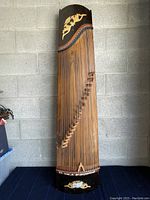 Full front view of 21-string guzheng against concrete block wall