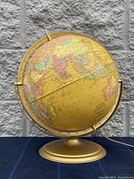 Front view of vintage golden globe lamp showing Asia and surrounding regions on the map.