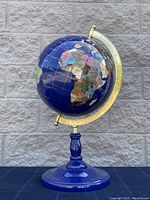 Front view of the semi-precious stone globe showing Africa prominently with its colorful stone inlays, blue base, and brass meridian.