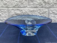 Side angle of blue Kosta Boda glass dish showing flared top and solid base.