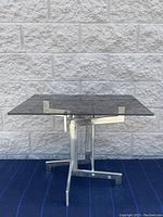 Front angle showing the smoked glass top and chrome base with geometric design.