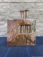 Front view of metallic brown ceramic vase with textured surface, two necks, and rectangular cutout