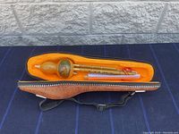 Opened leather case with gourd flute inside showing velvet lining and fit