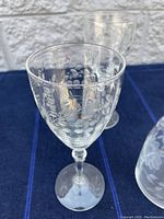 Close-up of one etched glass showing the floral and leaf etching details on the bowl and stem.