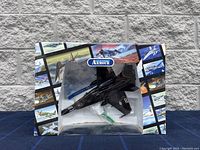 Front view of boxed Franklin Mint Precision Models F-18 Hornet aircraft model with the black and white box with multiple aircraft images and clear window.