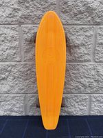 Top view of the skateboard showing the full length and shape against the wall.