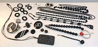 Full view of black jewelry collection including necklaces, bracelets, earrings, brooches, and pendant arranged on flat surface