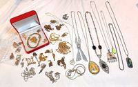 Overview of mixed gold and silver chains plus loose pendants on white surface