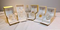 Full view of five perfume bottles in individual satin/sueded boxes showing mostly empty contents and one tall empty spray bottle without box.