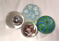 Overhead view of all four Murano glass paperweights on white background
