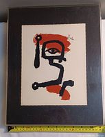 Full view of the silkscreen print in a black plastic frame with a taped measuring tape showing approx 14.5 inches width.