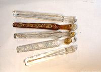 Five elongated glass perfume vials arranged horizontally on white background