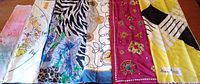 Lot overview showing five colorful silk scarves laid side by side, displaying various prints including floral, zebra pattern, and astrological themes.