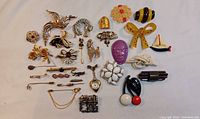 Overall assortment of 25 vintage pins and brooches on white background