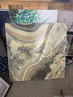 Abstract art piece with natural mineral-like pattern in mostly brownish and beige tones, square shape, glossy finish.