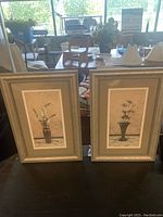 Two floral prints with light-colored ornate frames, each about 13x18 inches, depicting simple floral designs in vases.
