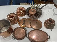 Copper pans, molds, lids, and stock pot arranged on countertop