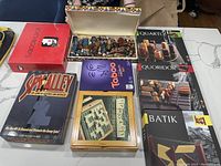 Full view of the lot showing boxed board games including Scattergories, Spy Alley, Taboo, Quarto, Quoridor, and Batik along with the Peruvian chess set box on top.
