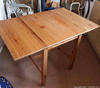 Photo of the IKEA LEKSVIK dining table fully extended with one leaf inserted showing the light wood finish and extendable ends.