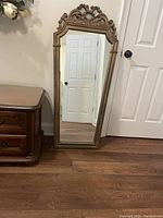 Front view showing the full vintage mirror with carved wooden frame and decorative crest at the top.
