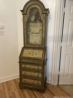 Front view of tall secretary desk showing glass door cabinet, drop front writing surface, and three drawers with floral motifs