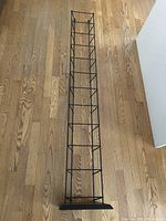 Top view photo of the black metal video tower showing the full length and shelving structure on wooden floor.