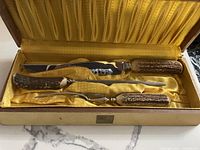 Open wooden box with yellow silk interior showing the 3-piece carving set inside, featuring stag horn handles on each tool.