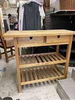 Full view of wooden butcher table showing top surface, drawers and slatted lower shelves.
