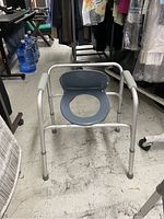Metal handicap toilet seat with blue padded seat and backrest, showing use and needing cleaning.