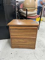 Front view of wooden nightstand showing two drawers and wood grain finish.