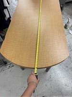 Photo showing the full length of the wooden table with a tape measure along its surface indicating length of approximately 65 inches.