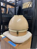 Full view of the vintage Oster hairdryer hood in cream and beige colors placed on a cushion.