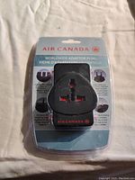 Photo of a new Air Canada Worldwide Adaptor Plug in original sealed packaging showing plug design and branding.