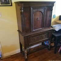 Full front view of antique wooden dining room hutch showing carved details, central door, and drawer beneath.