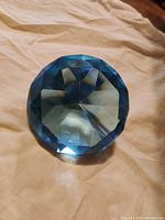 Top view of blue faceted glass diamond-shaped paperweight showing multiple facets and clear blue tint.