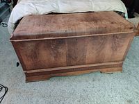 Front side of the rectangular cedar chest with natural wood finish and visible grain, closed lid.