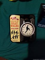 Monty Python Ministry of Silly Walks watch displayed in presentation tin showing front watch face and branded packaging.