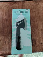 Multi-tool axe still sealed on green and white backing card with tree graphics.