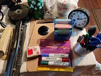 Photo of assorted office items including shamrock mugs, desk clock, post-it notes, dry erase markers, and clipboard.